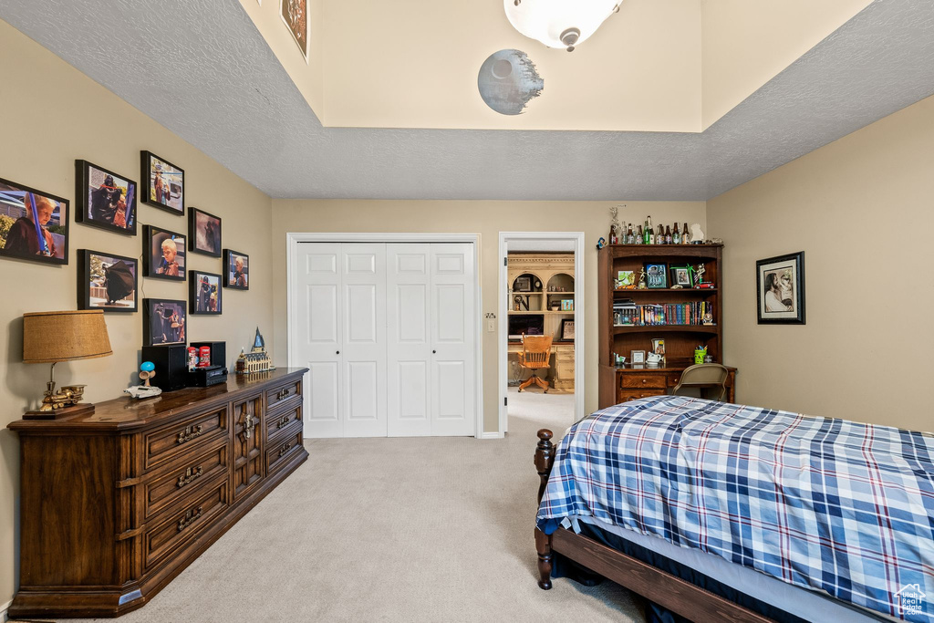 Bedroom featuring carpet, a closet, and a textured ceiling