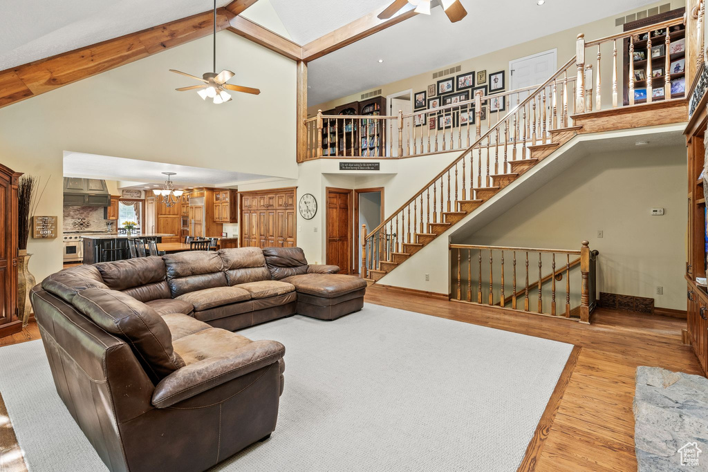 Living room with high vaulted ceiling, ceiling fan, and hardwood / wood-style floors