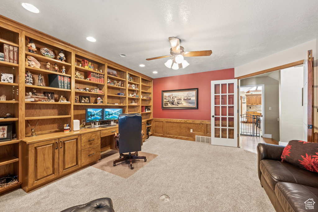 Carpeted office with ceiling fan and french doors