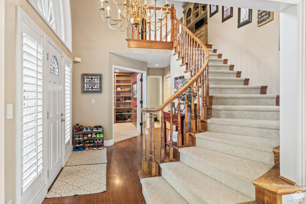 Entryway with a high ceiling, plenty of natural light, hardwood / wood-style floors, and a chandelier