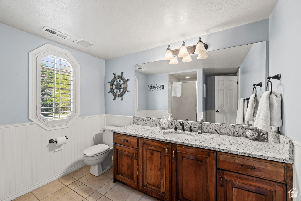 Bathroom with tile flooring, toilet, a textured ceiling, and large vanity