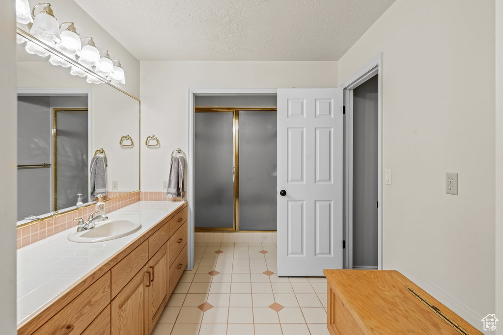 Bathroom featuring walk in shower, tile flooring, and vanity