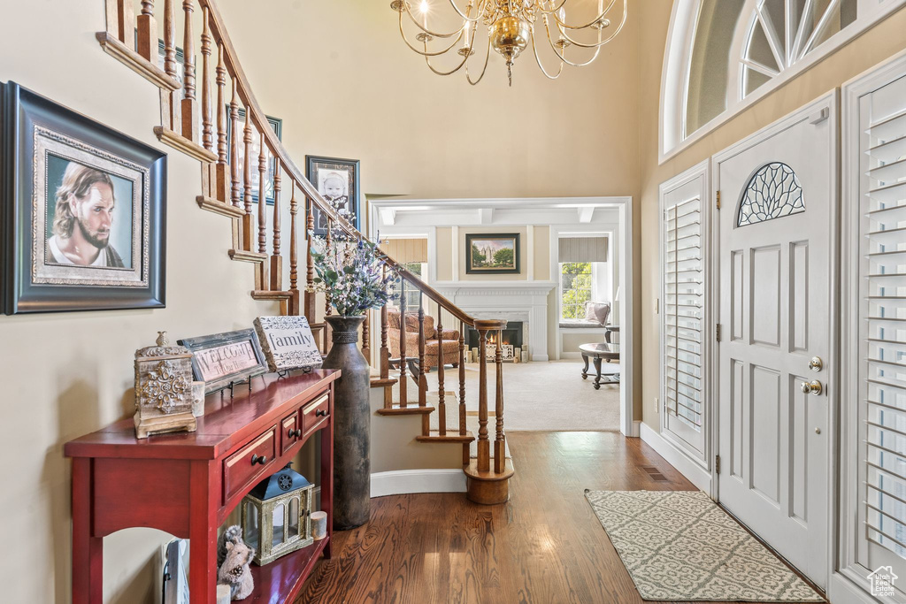 Entrance foyer with a notable chandelier, a towering ceiling, and wood-type flooring