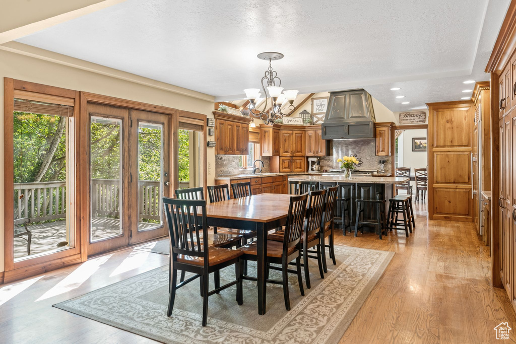 Dining space featuring sink, a chandelier, a textured ceiling, and light wood-type flooring