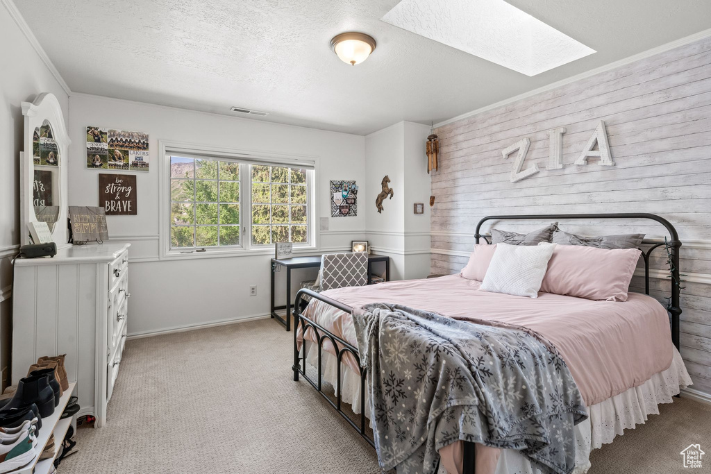 Carpeted bedroom with a textured ceiling, crown molding, and a skylight