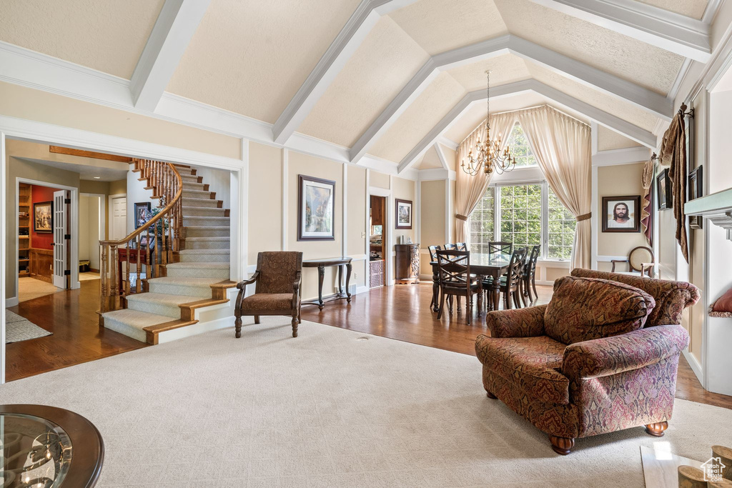 Living room with an inviting chandelier, lofted ceiling with beams, hardwood / wood-style flooring, and ornamental molding