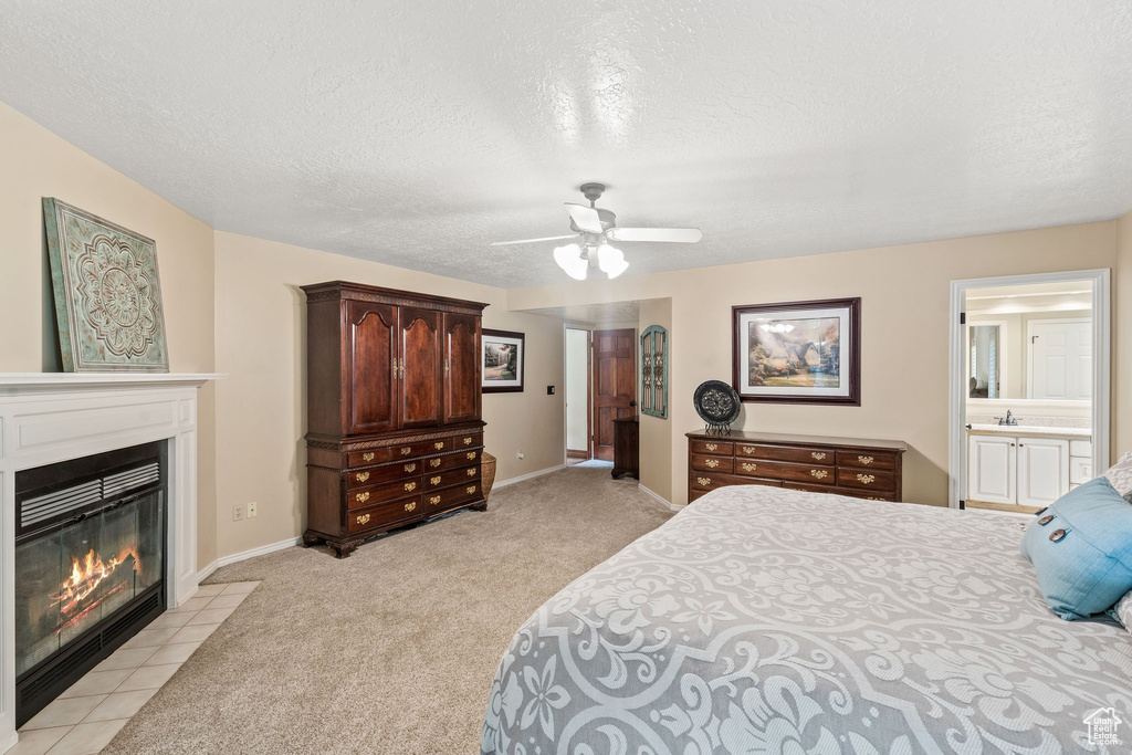 Carpeted bedroom featuring ceiling fan, a textured ceiling, and ensuite bath