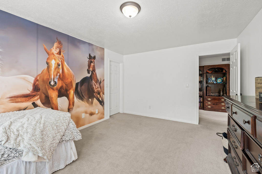 Bedroom featuring light carpet and a textured ceiling