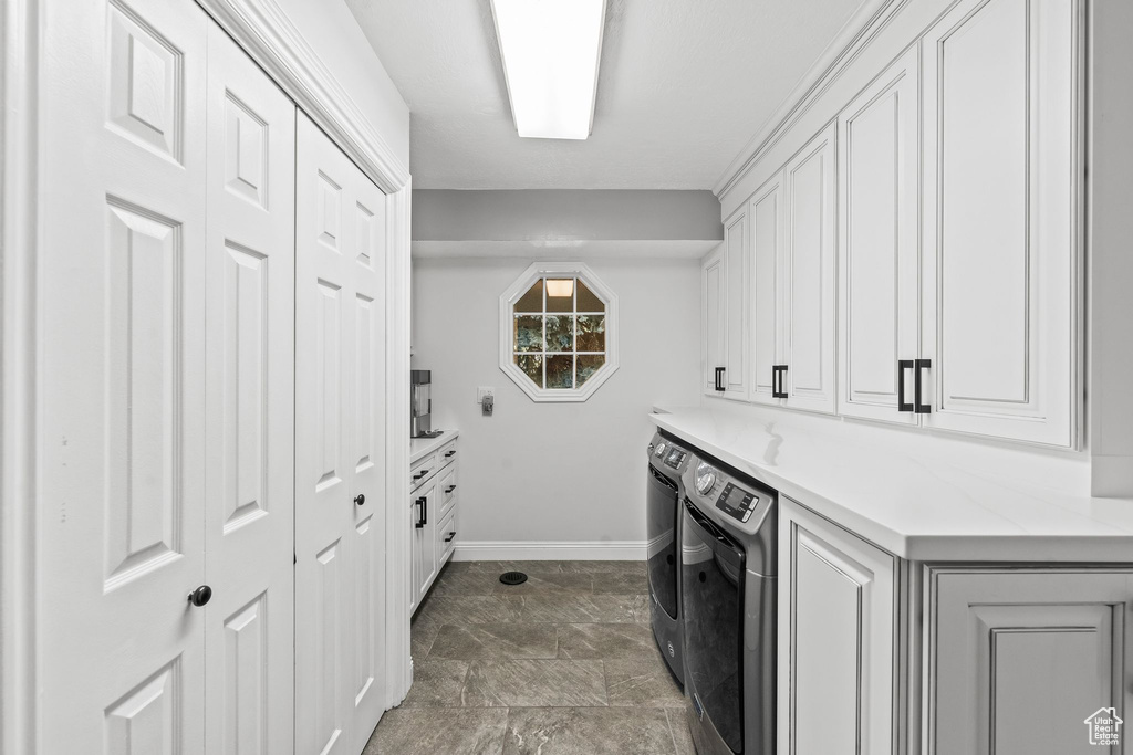 Washroom with separate washer and dryer, dark tile floors, and cabinets