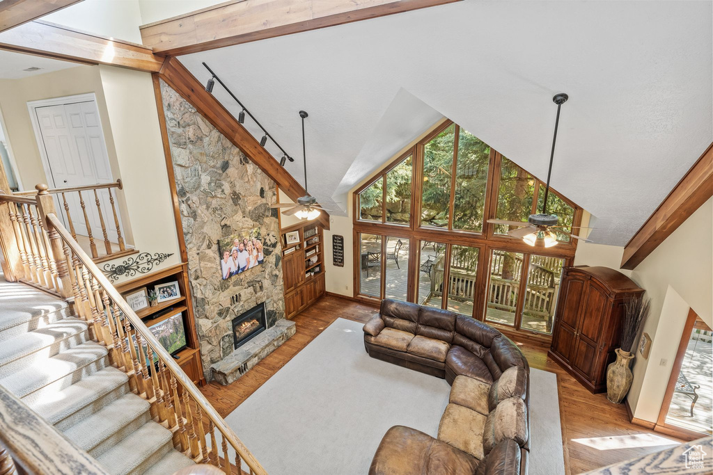 Living room with ceiling fan, hardwood / wood-style floors, beamed ceiling, a fireplace, and high vaulted ceiling