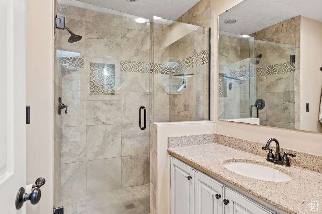 Bathroom featuring a shower with door and vanity