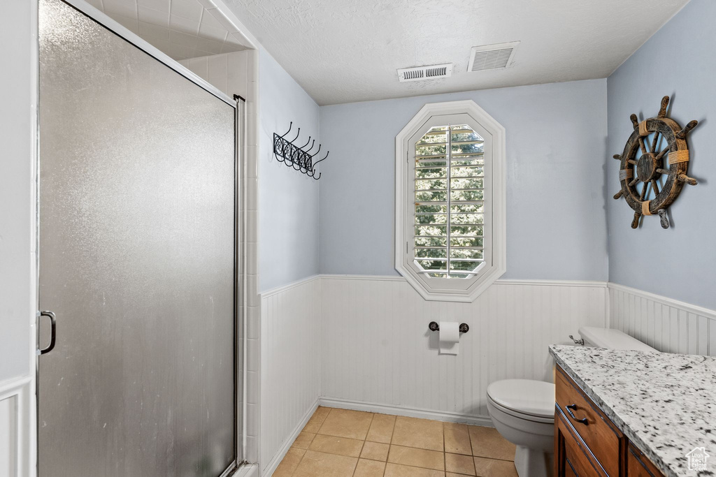 Bathroom with walk in shower, a textured ceiling, tile floors, toilet, and vanity