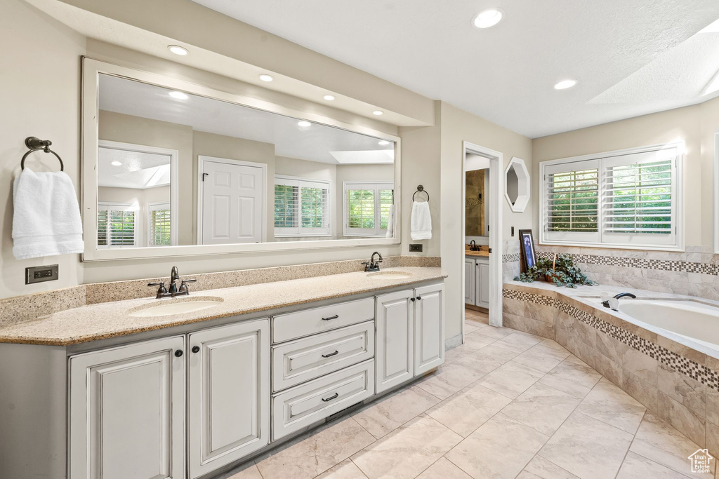 Bathroom featuring double sink vanity, plenty of natural light, and tiled tub