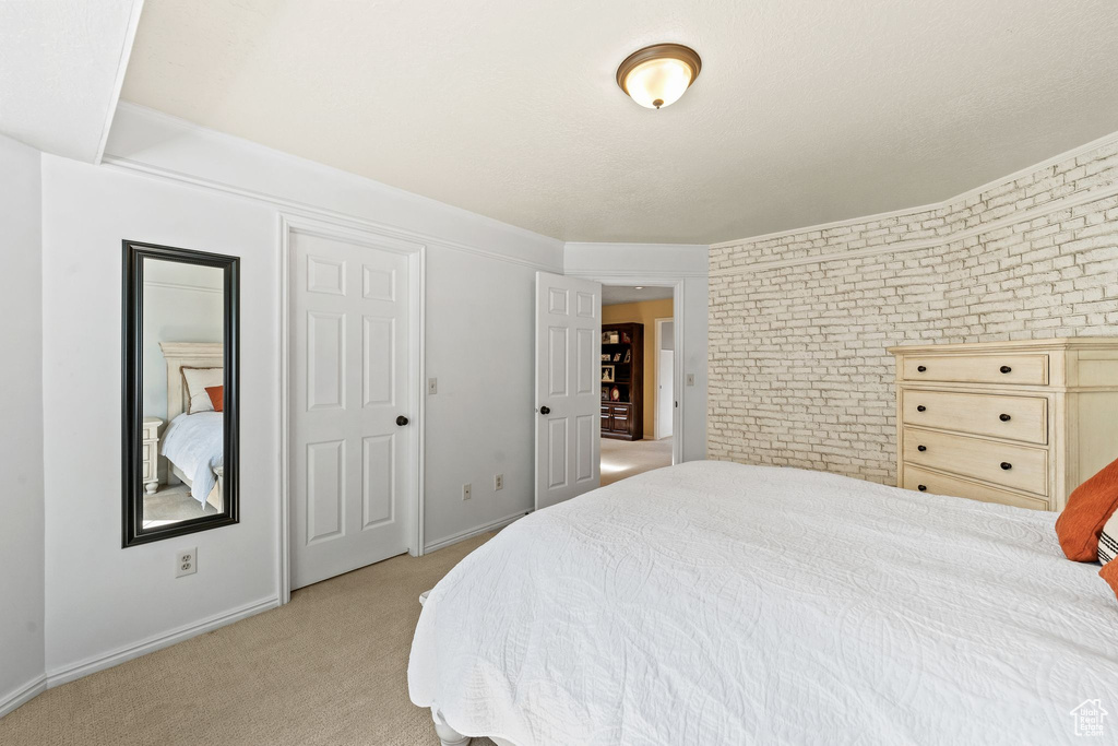 Bedroom with light carpet and brick wall