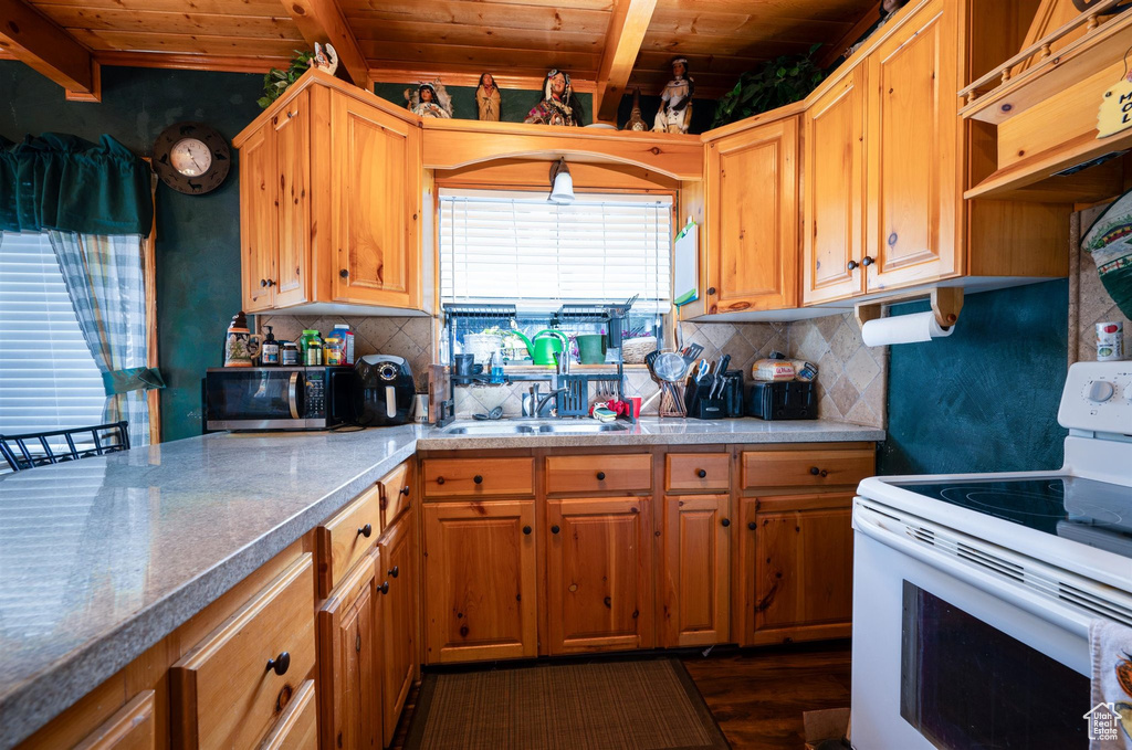 Kitchen with wooden ceiling, white electric stove, and backsplash