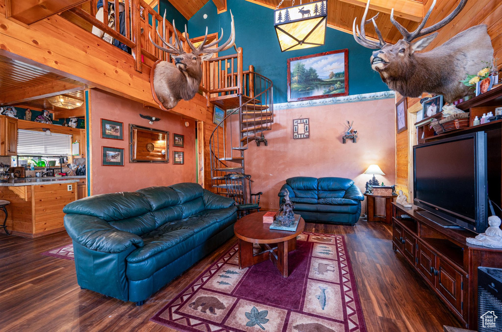 Living room featuring dark hardwood / wood-style floors, beamed ceiling, and a towering ceiling