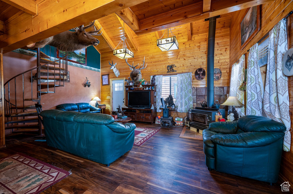 Living room featuring wooden ceiling, hardwood / wood-style flooring, beam ceiling, wood walls, and a wood stove