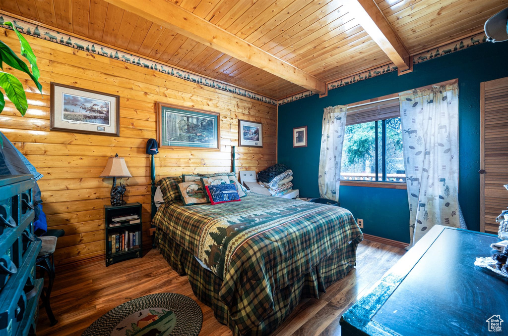 Bedroom featuring beam ceiling, wooden ceiling, rustic walls, and dark wood-type flooring