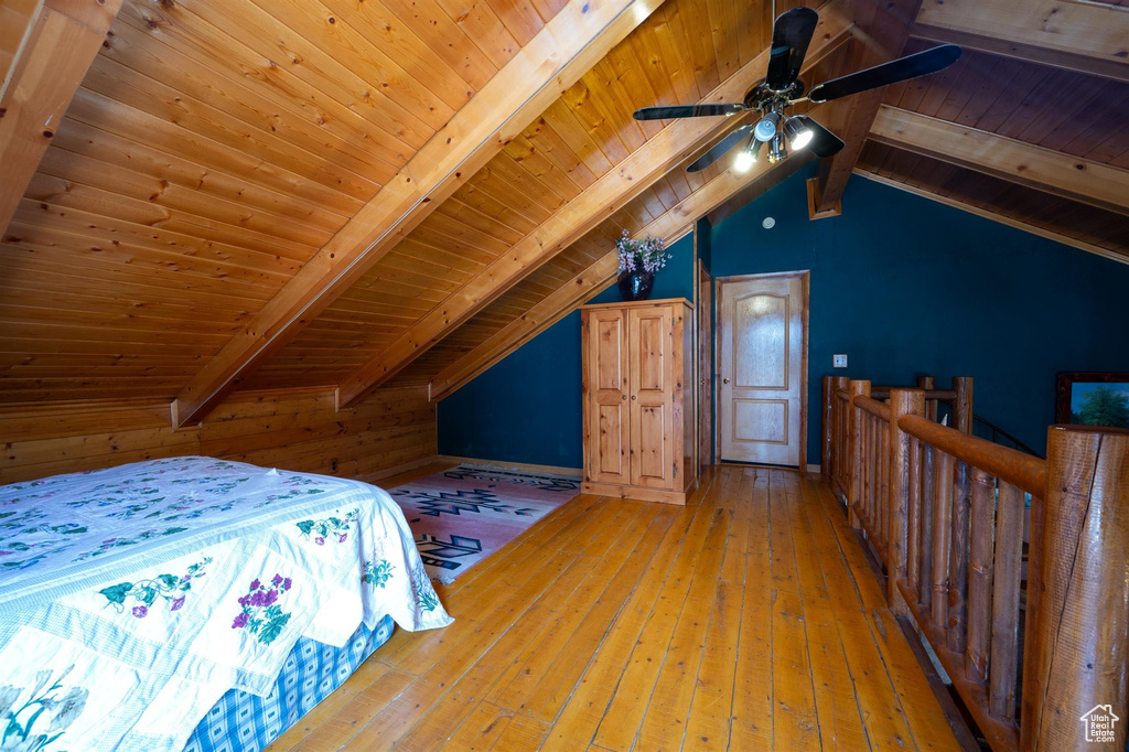 Bedroom featuring wood walls, ceiling fan, wooden ceiling, wood-type flooring, and lofted ceiling with beams