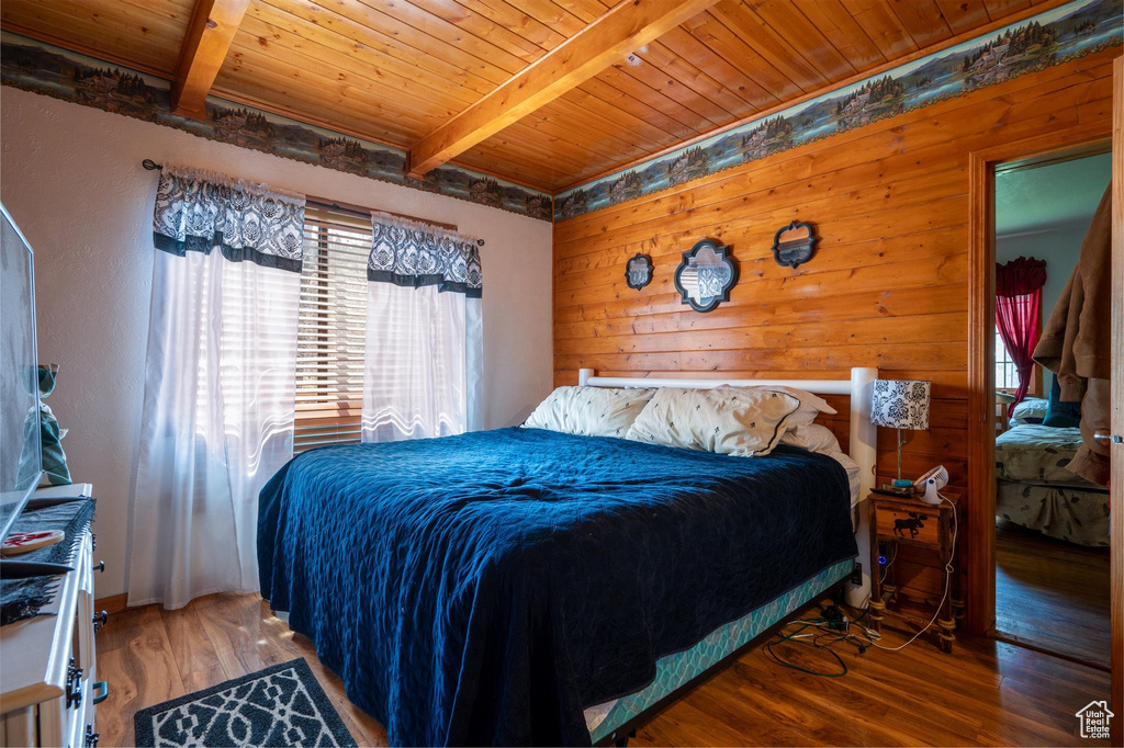 Bedroom featuring wooden walls, beam ceiling, wood-type flooring, and wooden ceiling