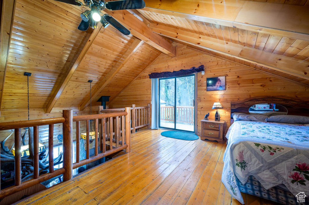 Bedroom featuring lofted ceiling with beams, wood ceiling, wood walls, and hardwood / wood-style floors