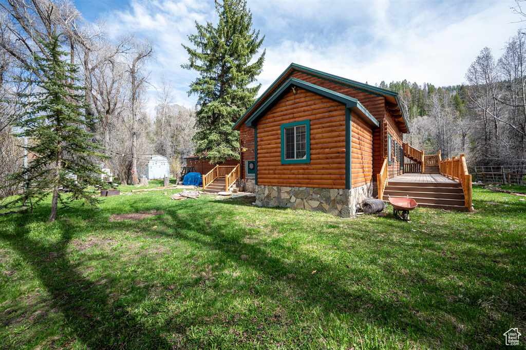 View of home's exterior featuring a lawn and a wooden deck