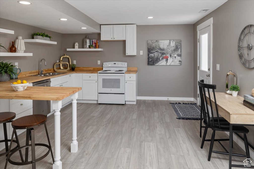 Kitchen featuring light hardwood / wood-style floors, white cabinetry, butcher block countertops, electric stove, and sink