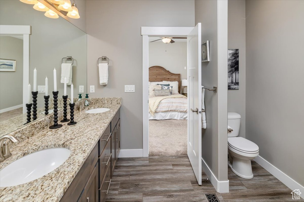 Bathroom with ceiling fan, double vanity, toilet, and wood-type flooring