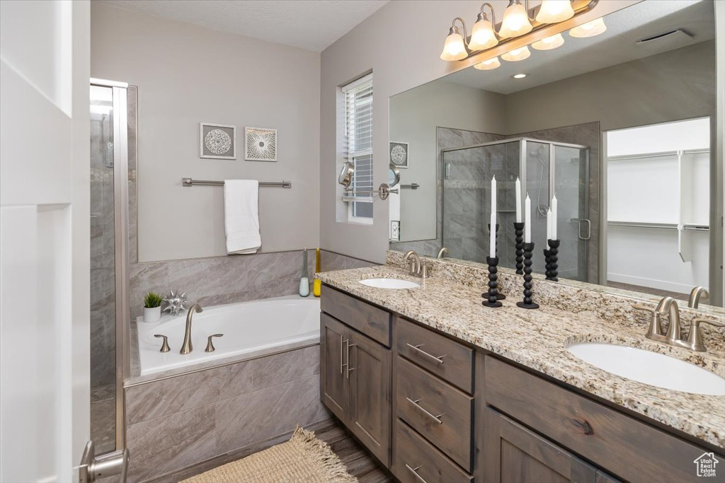 Bathroom featuring shower with separate bathtub and double sink vanity