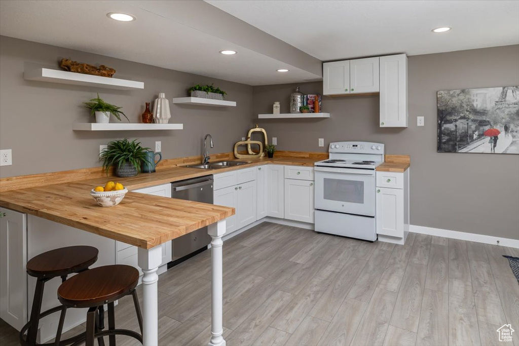 Kitchen featuring sink, white cabinetry, wood counters, and white electric range