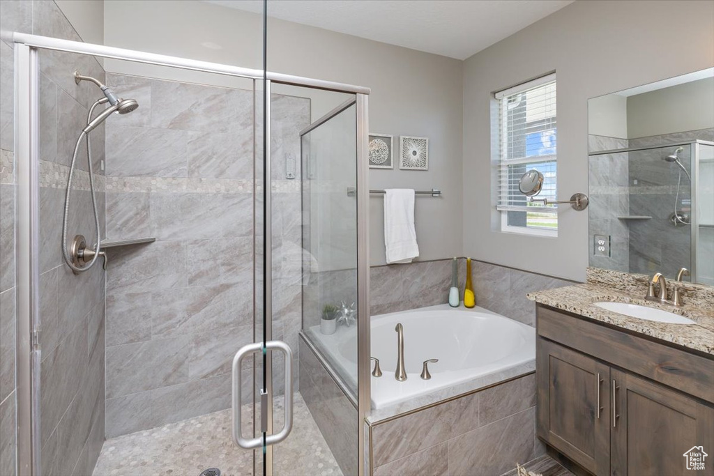 Bathroom featuring vanity with extensive cabinet space and separate shower and tub