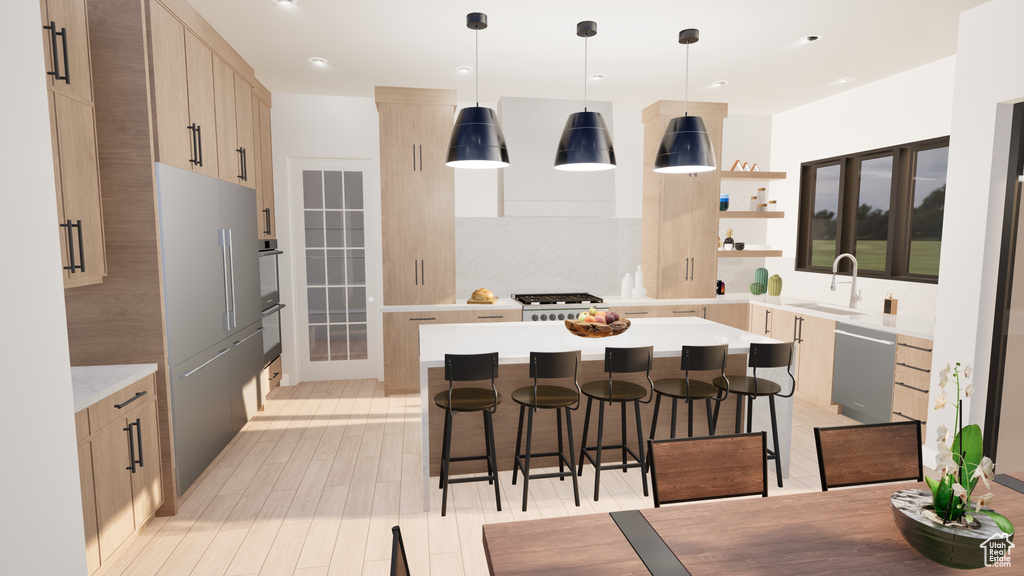 Kitchen with light hardwood / wood-style floors, a kitchen island, hanging light fixtures, a breakfast bar area, and sink