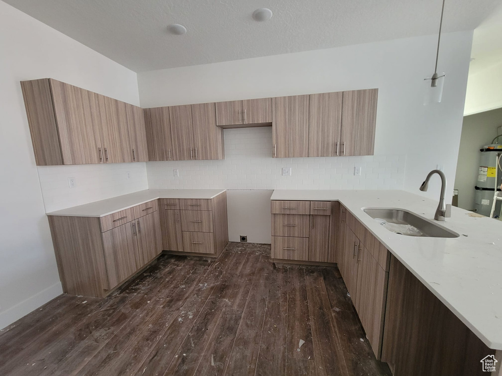 Kitchen featuring sink, dark wood-type flooring, and backsplash