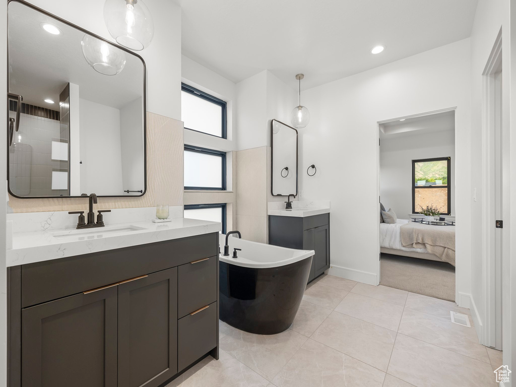 Bathroom featuring a bath to relax in, vanity, and tile floors