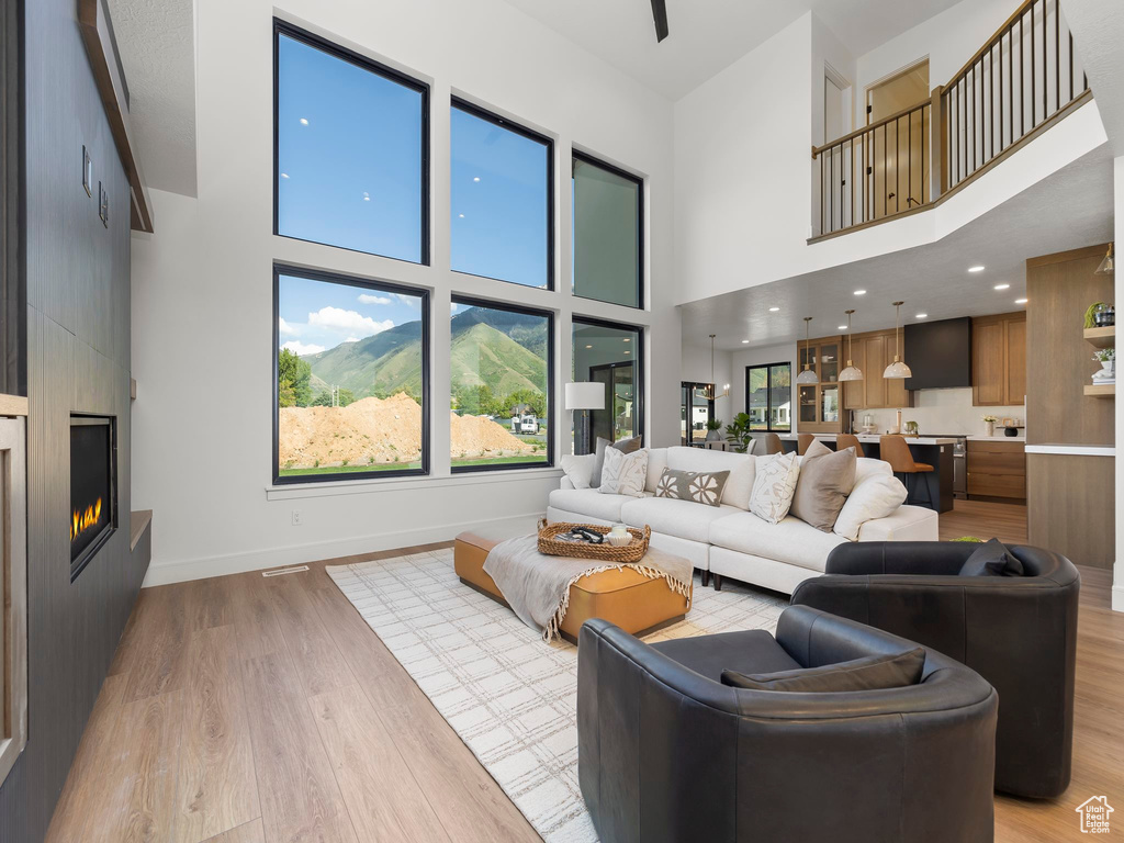 Living room featuring light hardwood / wood-style floors, a large fireplace, and a towering ceiling