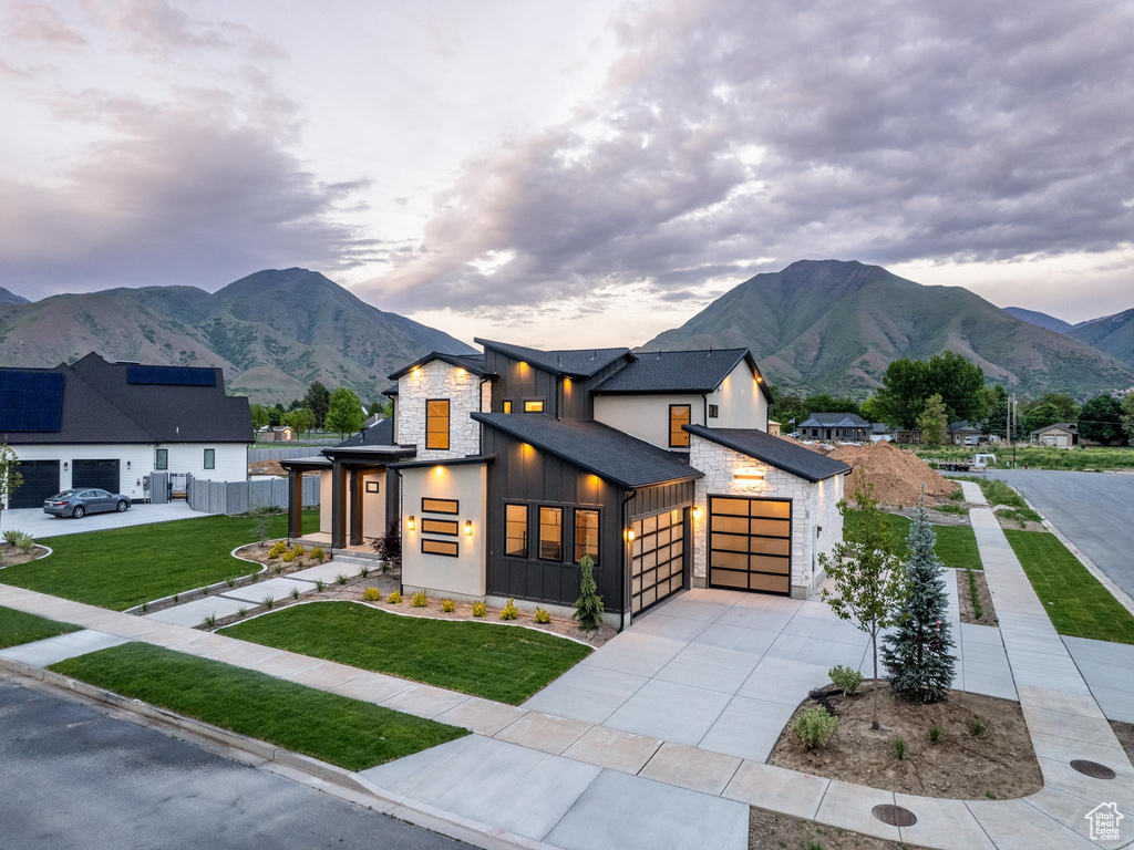 View of front of home with a garage, a mountain view, and a front yard