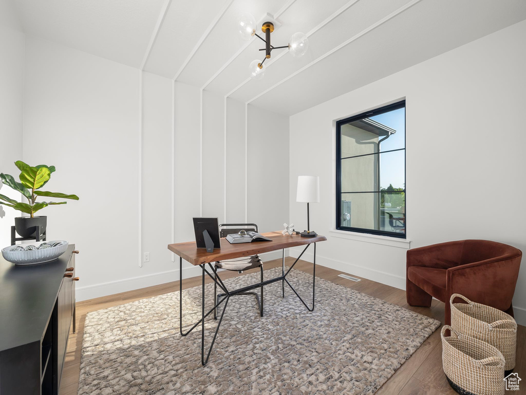 Office space featuring a notable chandelier and hardwood / wood-style floors