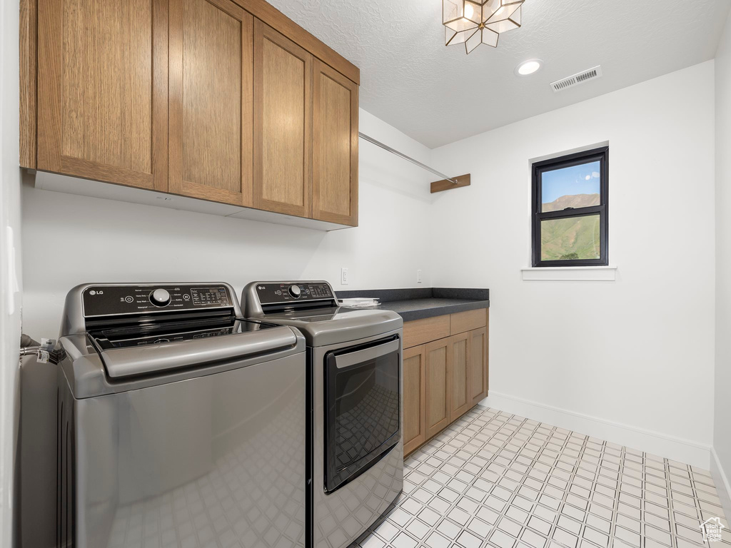 Washroom featuring separate washer and dryer, cabinets, and light tile floors