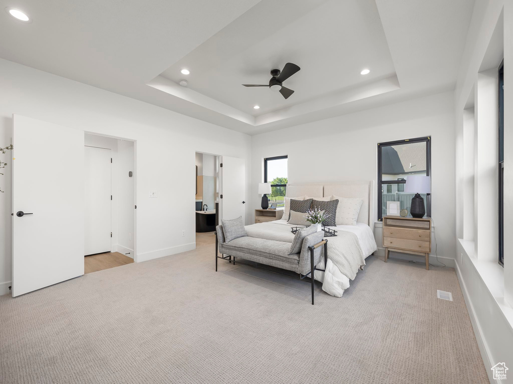 Carpeted bedroom featuring ceiling fan and a raised ceiling