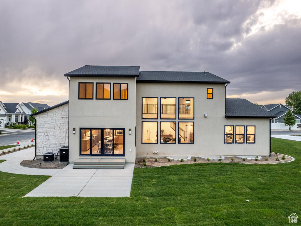 Back house at dusk featuring a yard