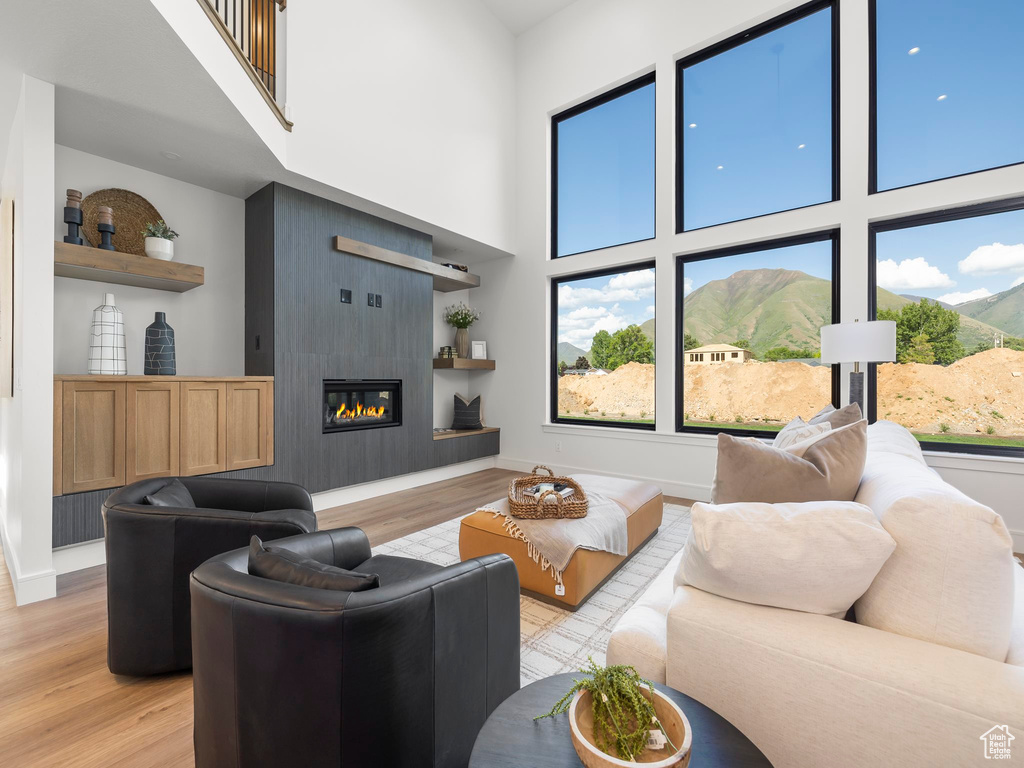 Living room featuring light hardwood / wood-style floors, a fireplace, a towering ceiling, and a mountain view