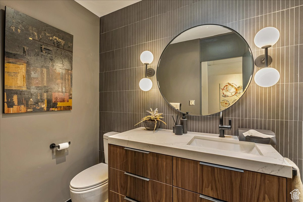 Bathroom featuring tile walls, oversized vanity, and toilet