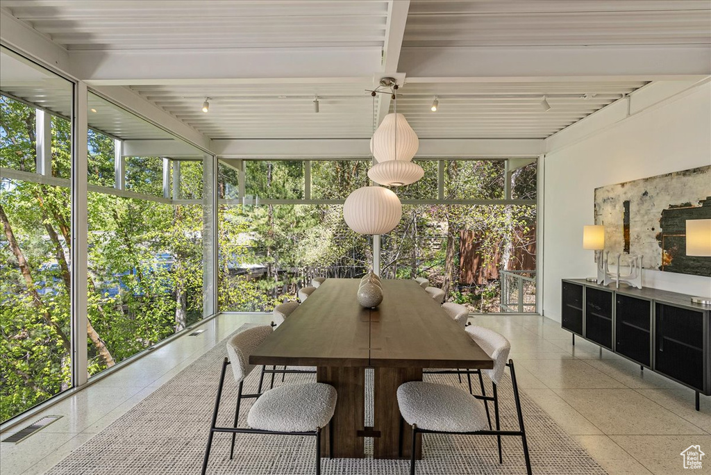 Sunroom featuring beam ceiling and a healthy amount of sunlight