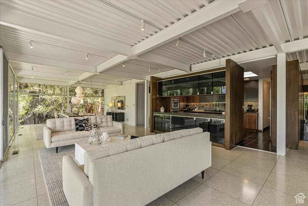 Living room with beam ceiling, tile floors, and rail lighting