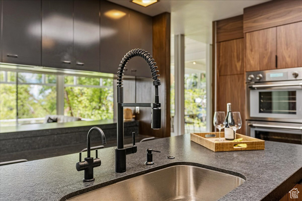 Kitchen with stainless steel double oven, a wealth of natural light, and sink