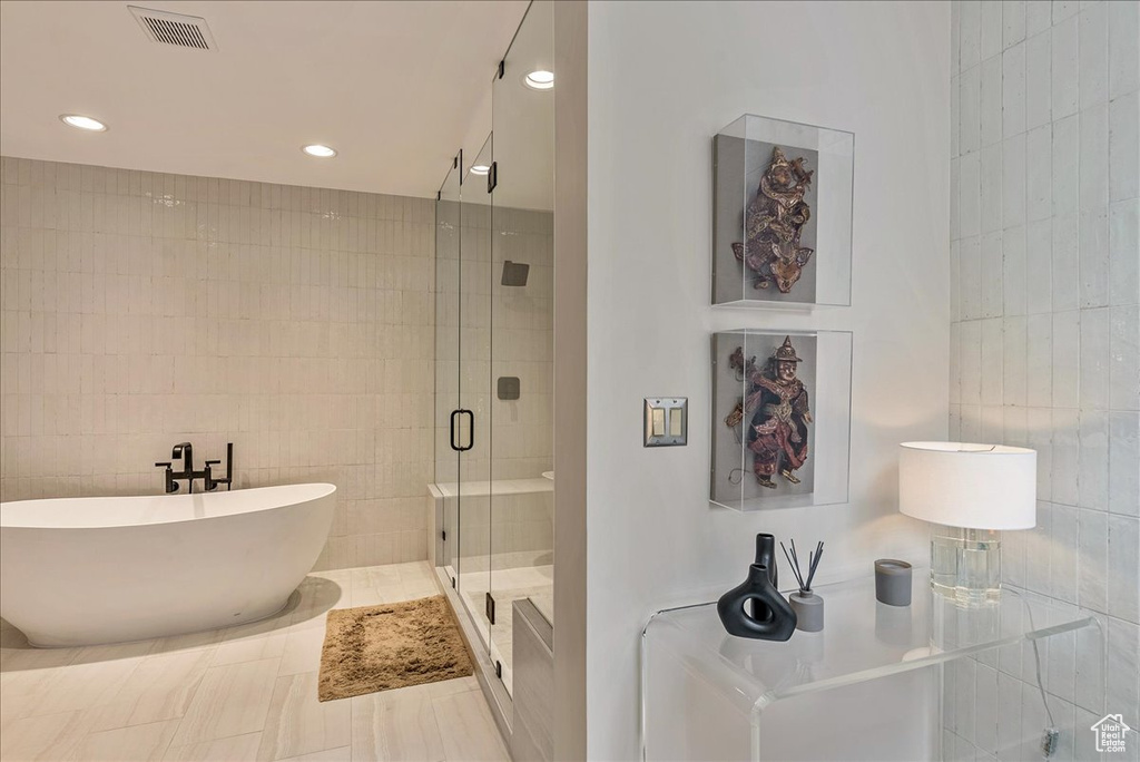 Bathroom with plus walk in shower, tile flooring, and tile walls