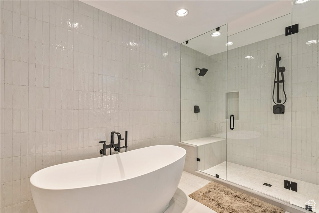 Bathroom featuring tile flooring, tile walls, and a shower with door