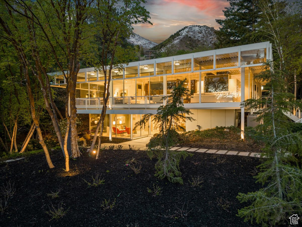 Back house at dusk featuring a mountain view and a patio