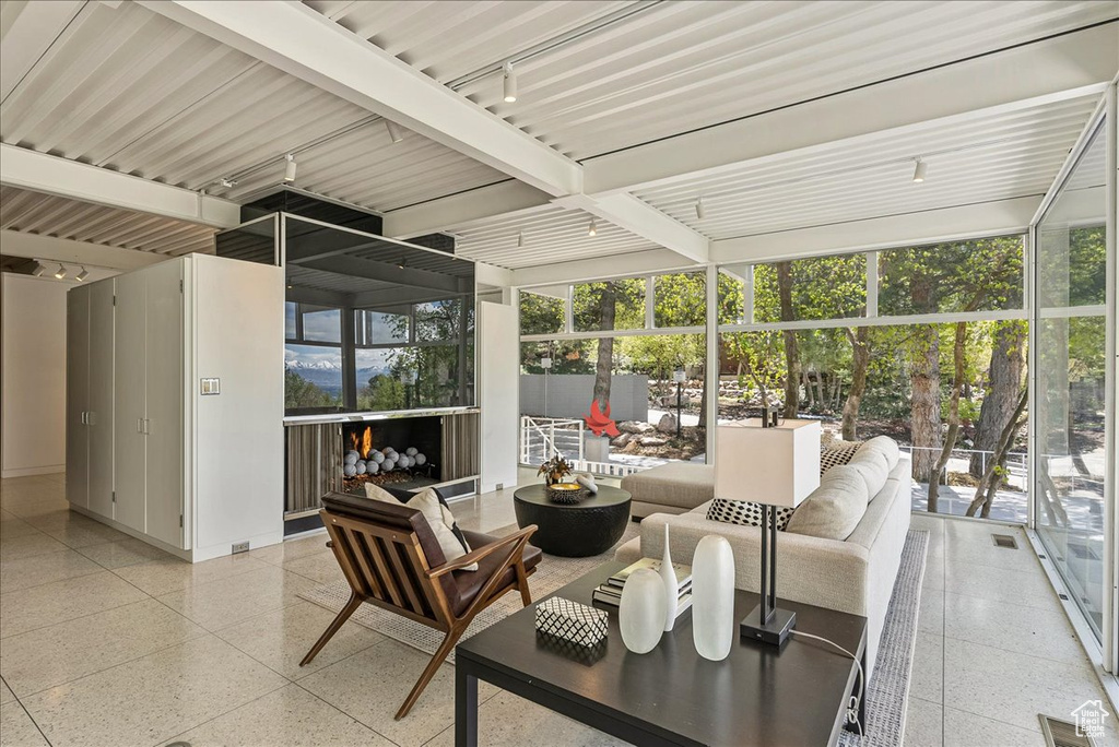 Sunroom / solarium featuring track lighting and beam ceiling