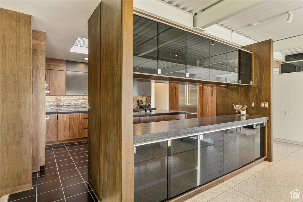 Kitchen featuring tile flooring, backsplash, track lighting, and a skylight